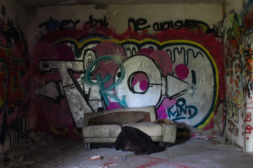 Ein Raum mit Graffiti an einer Wand. Ein Sofa steht im Raum.